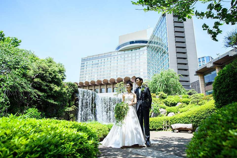 日本庭園の大滝の前で記念撮影するウエディングドレスとタキシード姿の夫婦